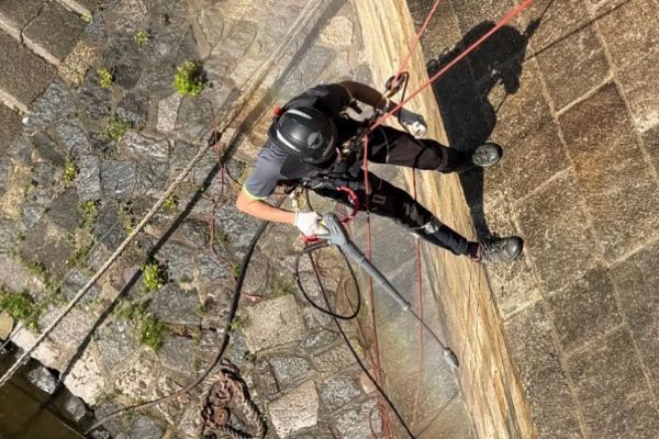 Na Karlově mostě probíhá ruční čištění řas a zeleně. Práce jsou bez uzavírek, technici pracují na lanech